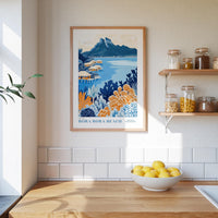 a kitchen scene with a framed poster of a tropical beach landscape hanging on the wall above a wooden countertop with a bowl of lemons.