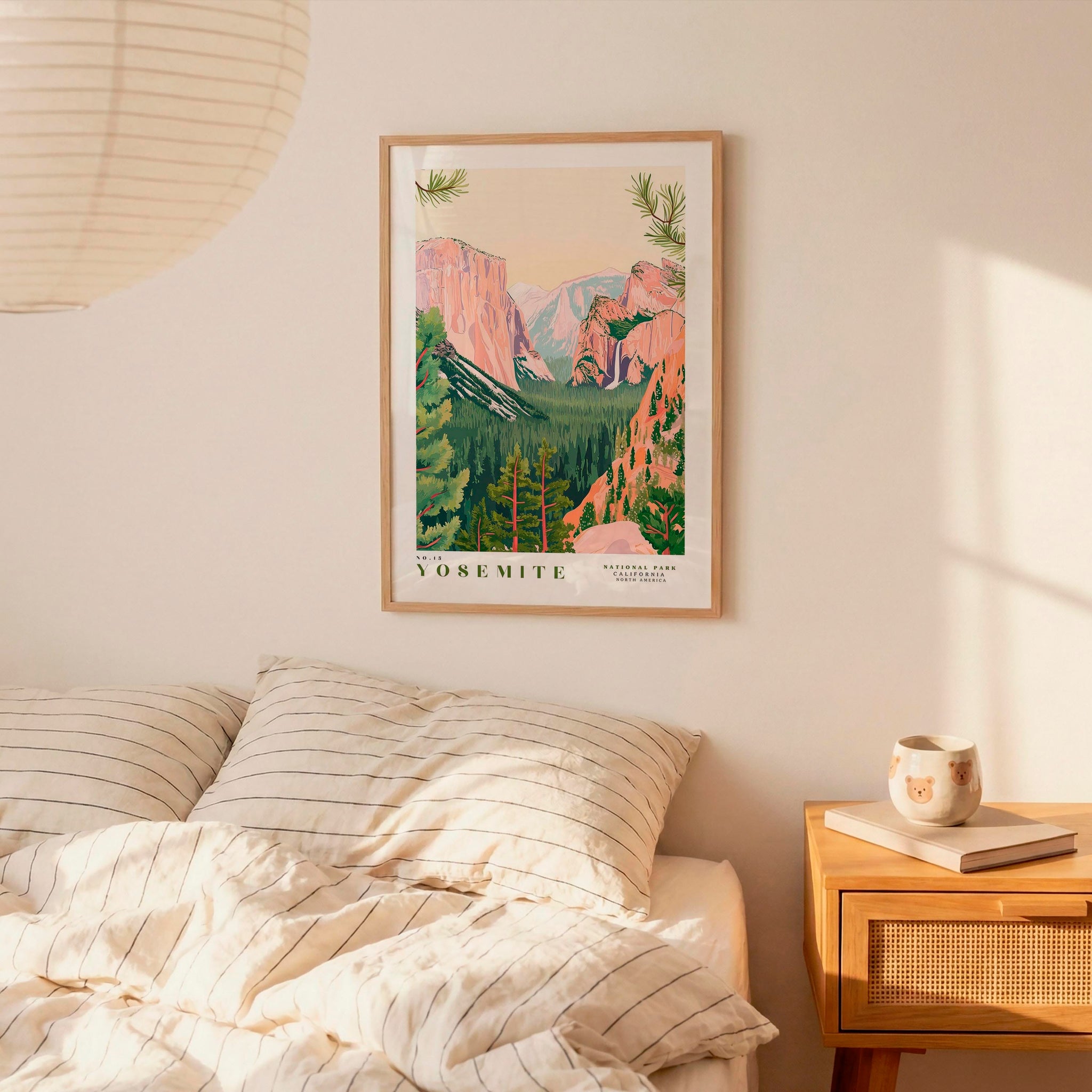 a framed poster of Yosemite National Park hanging on a wall above a bed with striped pillows.