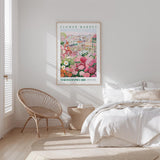 a bedroom with a bed, a wicker chair, and a framed poster of a flower market.