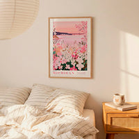 a bedroom scene with a framed poster of a floral landscape hanging on the wall above a bed with striped pillows.