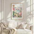 a framed poster of a cityscape with a flower market in the background, hanging on a wall above a white couch with a blanket draped over it.