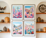 four framed prints of flower market scenes from different cities, including London, Rome, Athens, and Seville, displayed on a wall above wooden shelves with various decorative items.
