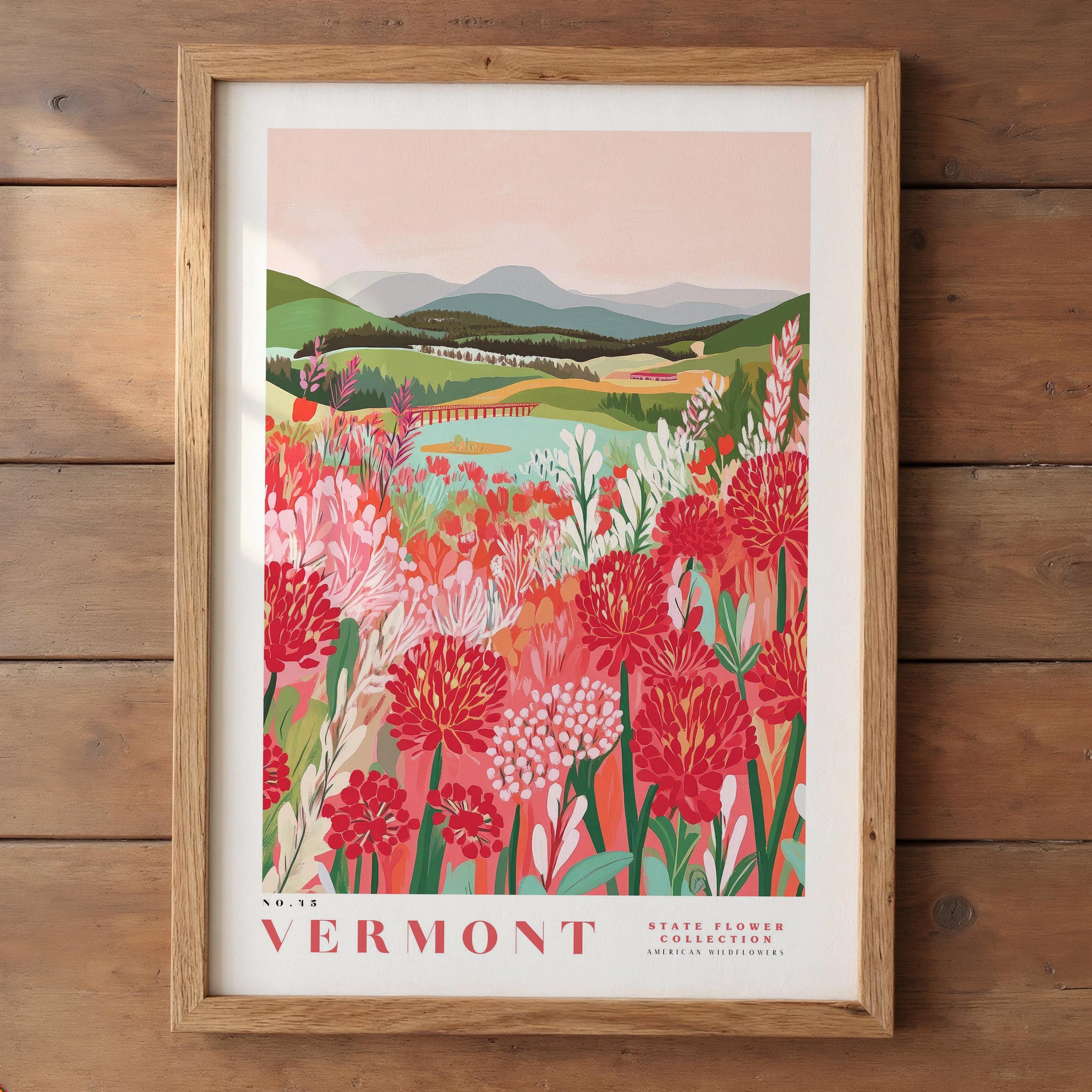 The image is a framed poster depicting a scenic landscape of a mountainous area with a river and a field of colorful flowers.