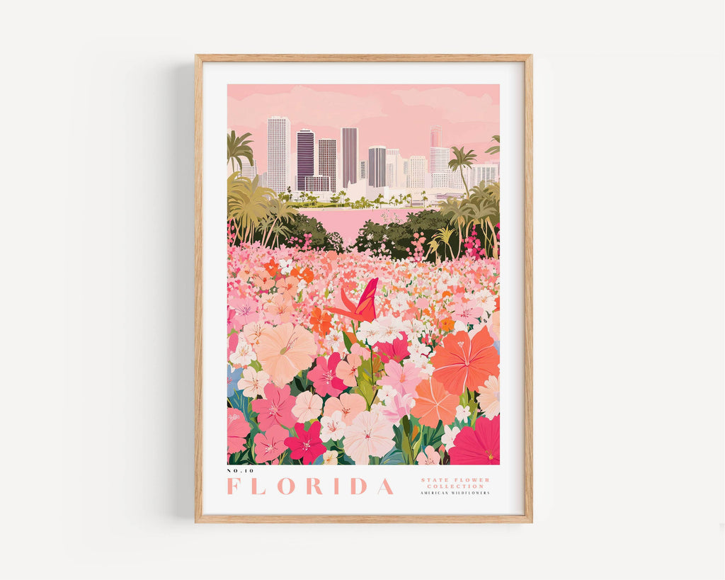 A framed poster depicting a vibrant cityscape with a field of colorful flowers in the foreground, including pink, orange, and white flowers.
