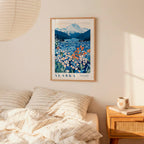 a bedroom scene with a framed poster of a mountain landscape hanging on the wall above a bed with striped pillows.