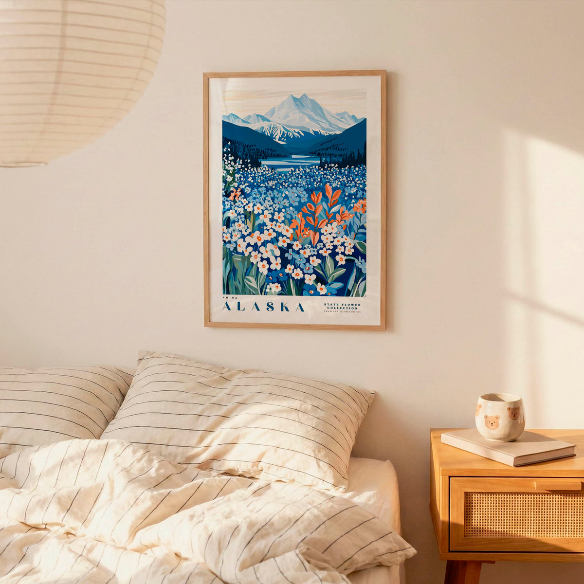 a bedroom scene with a framed poster of a mountain landscape hanging on the wall above a bed with striped pillows.