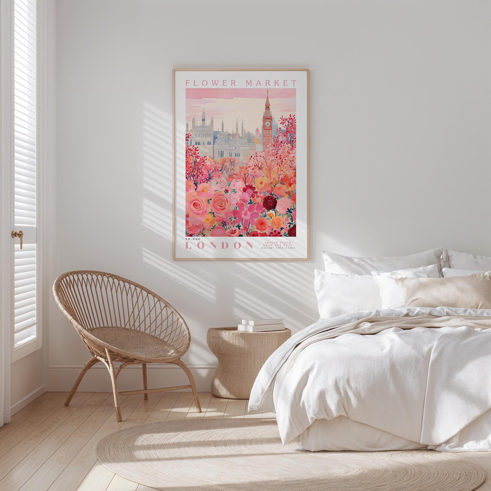 a bedroom with a large floral print hanging on the wall, featuring a cityscape and a clock tower. The room has a white bed, a woven chair, and a small side table.