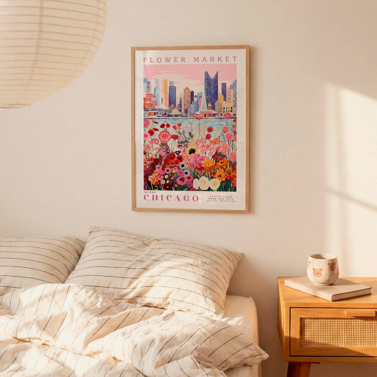 a framed poster of a cityscape with a flower market in Chicago, hanging on a wall above a bed with striped pillows.
