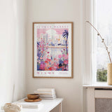 a framed poster of a colorful, floral-themed cityscape hanging on a wall in a room.