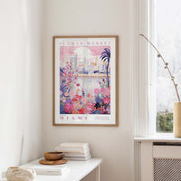 a framed poster of a colorful, floral-themed cityscape hanging on a wall in a room.