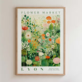 The image is a framed poster or print featuring a vibrant and colorful illustration of various flowers and plants, including tulips, daffodils, and other blooms. The poster is titled "Flower Market" and is framed with a wooden border.
