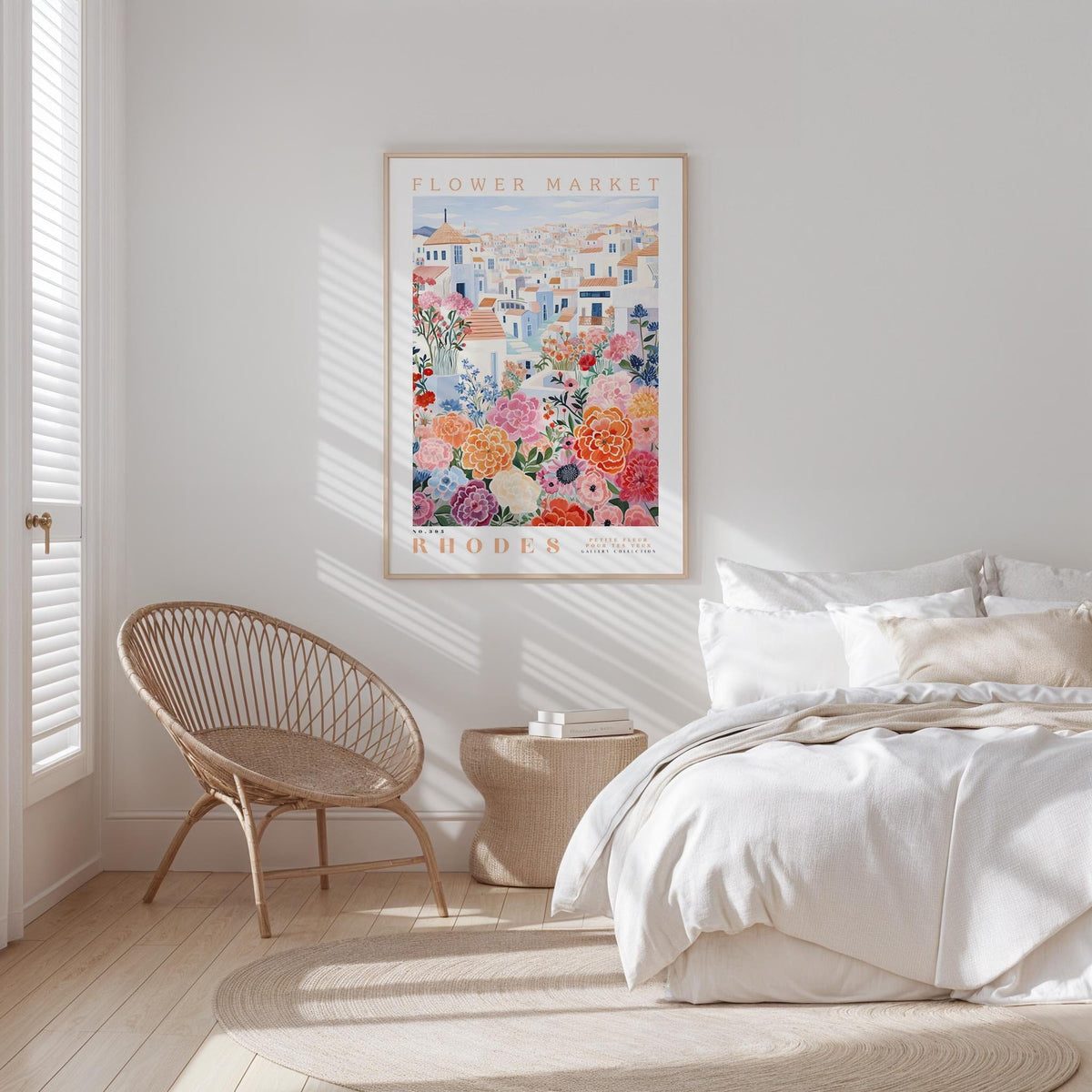 a bedroom with a bed, a woven chair, and a framed poster of a colorful floral scene hanging on the wall.