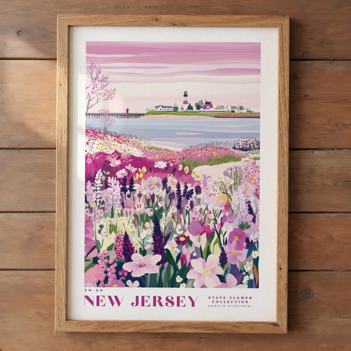 A framed poster depicting a scenic landscape with a lighthouse, a body of water, and a field of colorful flowers.