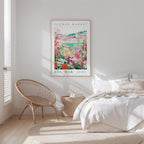 a bedroom with a bed, a woven chair, and a framed poster of a flower market on the wall.