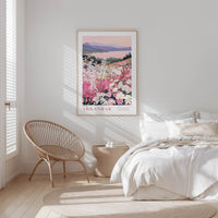 A bedroom with a large bed, a woven chair, and a framed poster of a floral landscape hanging on the wall.
