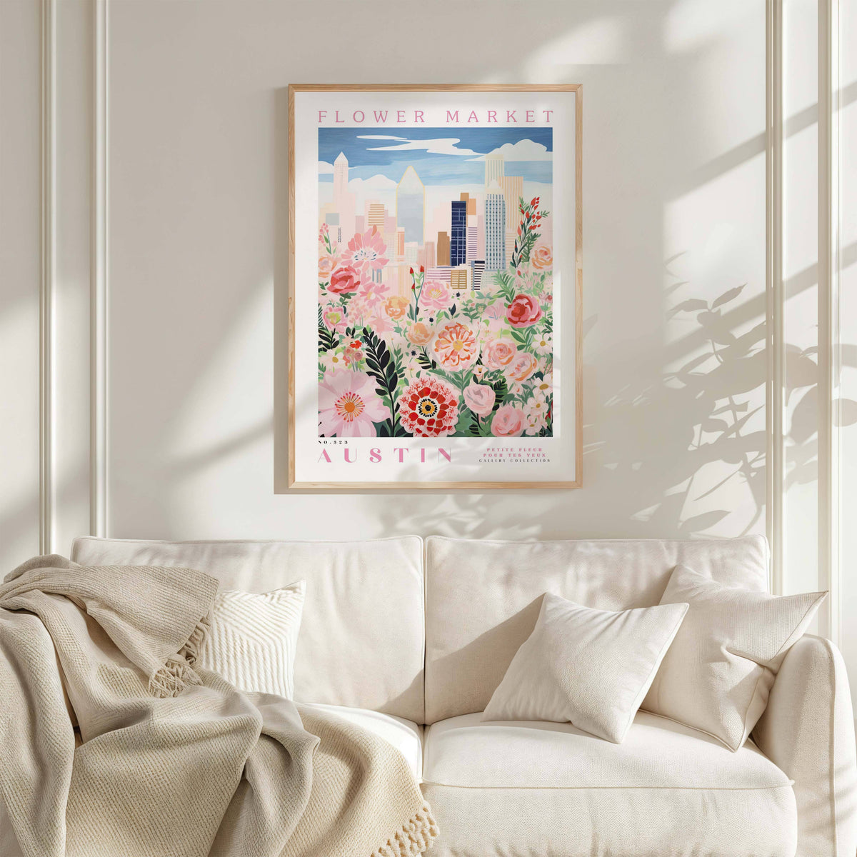 a framed poster of a cityscape with flowers hanging on a wall above a white couch with pillows.