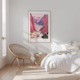 a bedroom with a large poster of a desert landscape hanging on the wall, featuring a canyon and mountains. The room has a white color scheme, with a bed, a woven chair, and a small side table.