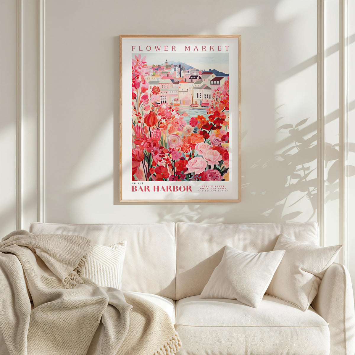 a framed poster of a flower market, with a white sofa and a plant in the foreground.