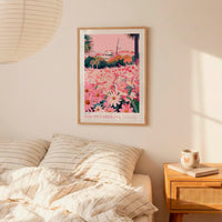 a bedroom scene with a framed poster of a field of flowers hanging on the wall above a bed with striped pillows.