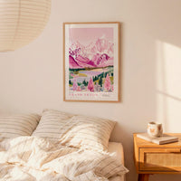 a bedroom scene with a framed poster of a mountain landscape hanging on the wall above a bed with striped bedding.