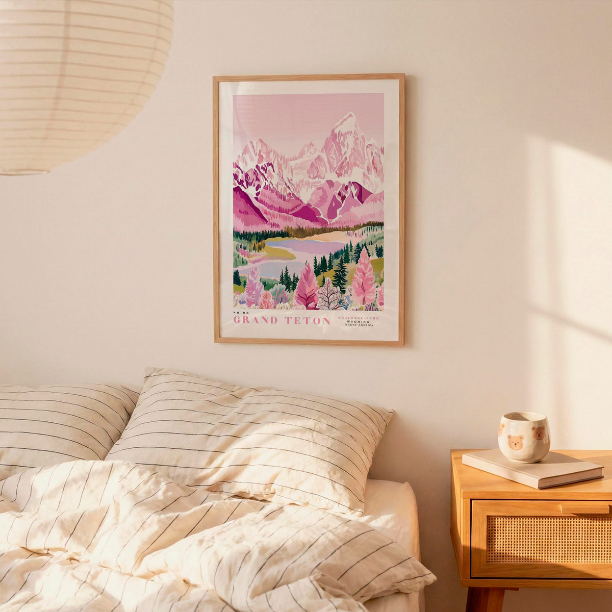 a bedroom scene with a framed poster of a mountain landscape hanging on the wall above a bed with striped bedding.