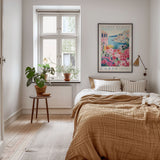 a cozy bedroom with a large bed, a wooden nightstand, and a window with a plant on the sill. The room has a warm, inviting atmosphere with a neutral color palette and natural elements like the potted plant and the rug.