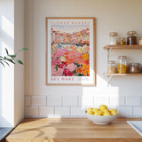 a kitchen scene with a framed poster of a flower market on the wall, a wooden counter with a bowl of lemons, and shelves displaying various jars and containers.