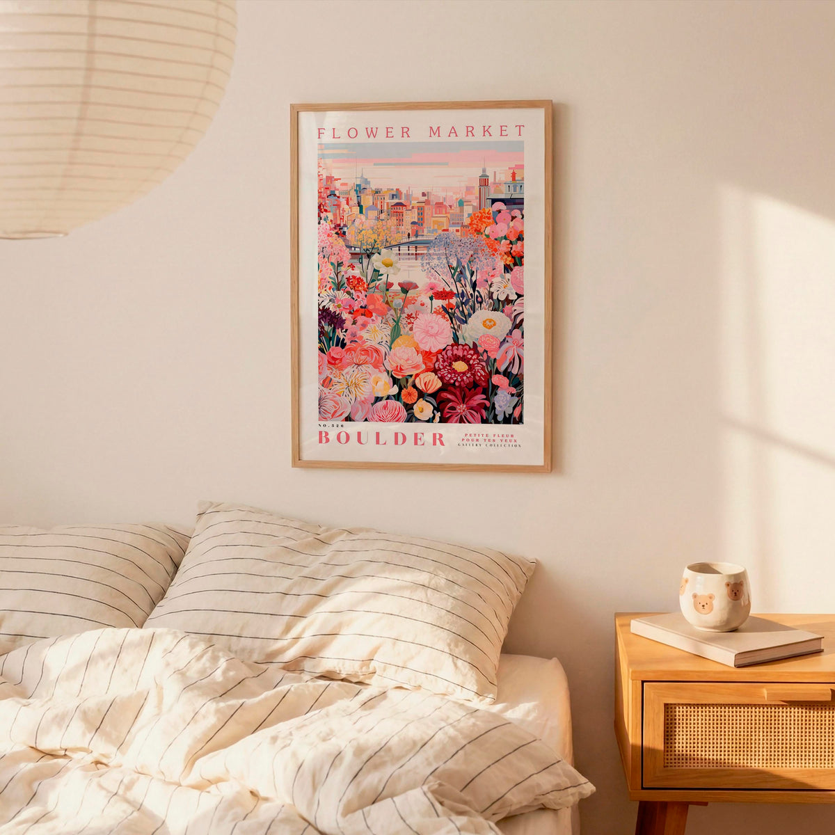 a bedroom setting with a framed poster of a colorful floral scene hanging on the wall above a bed with striped pillows.