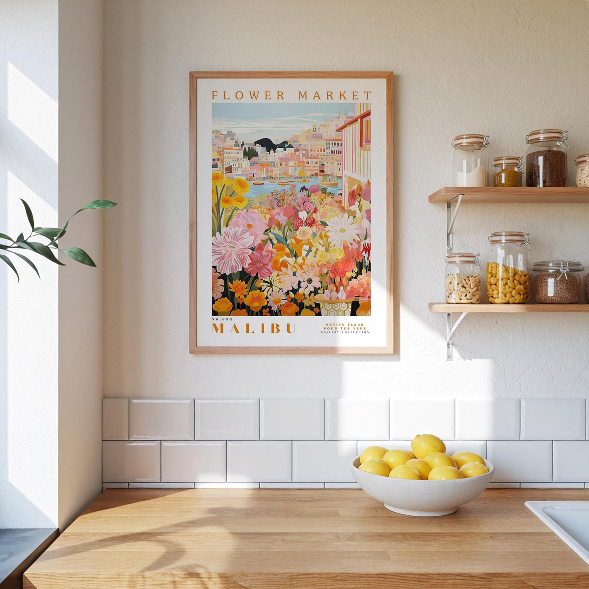 a framed poster of a colorful floral scene hanging on a wall above a wooden countertop with a bowl of lemons.