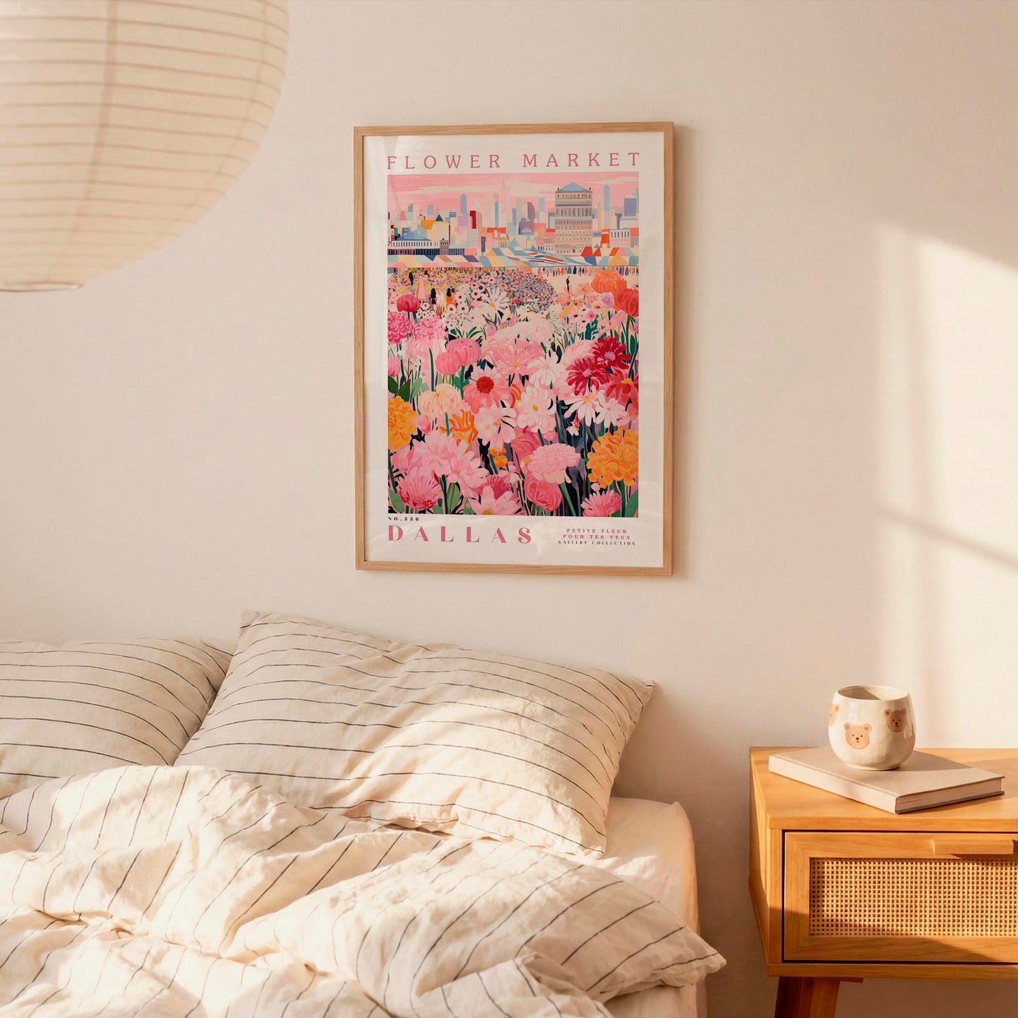 a bedroom scene with a framed poster of a flower market in Dallas hanging on the wall above a bed with striped pillows.