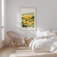 a serene bedroom scene with a large bed, a woven chair, and a framed print of a landscape with yellow flowers and green foliage.
