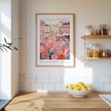 a kitchen scene with a framed poster of a flower market in the background, a wooden counter with a bowl of lemons, and shelves displaying various jars and containers.