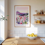a kitchen scene with a framed poster of a colorful floral landscape hanging on the wall above a wooden countertop with a bowl of lemons.