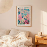 a bedroom setting with a framed poster of a colorful floral scene hanging on the wall above a bed with striped pillows.