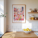 a framed poster of a flower market in Memphis, Tennessee, hanging on a wall above a wooden counter with a bowl of lemons.