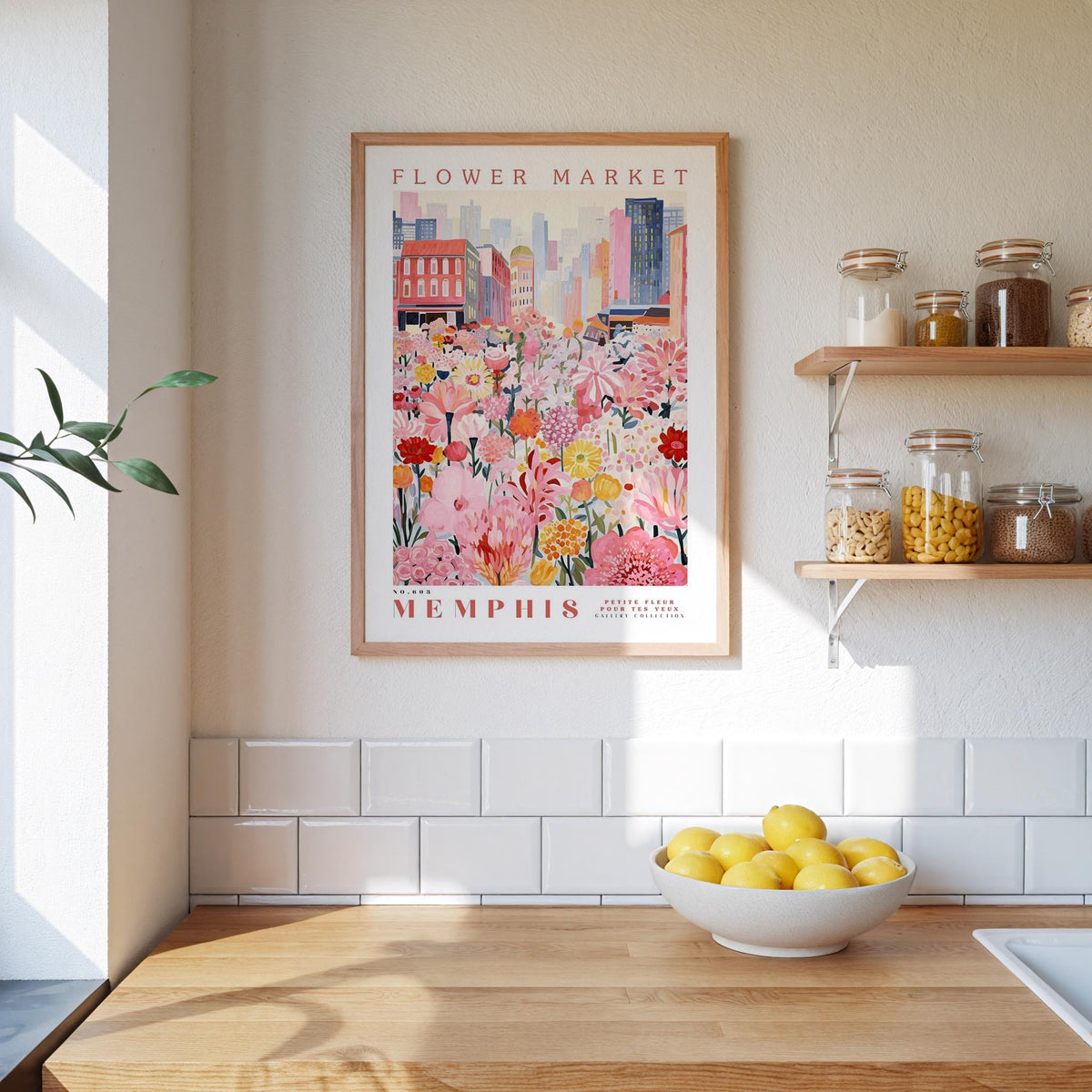 a framed poster of a flower market in Memphis, Tennessee, hanging on a wall above a wooden counter with a bowl of lemons.