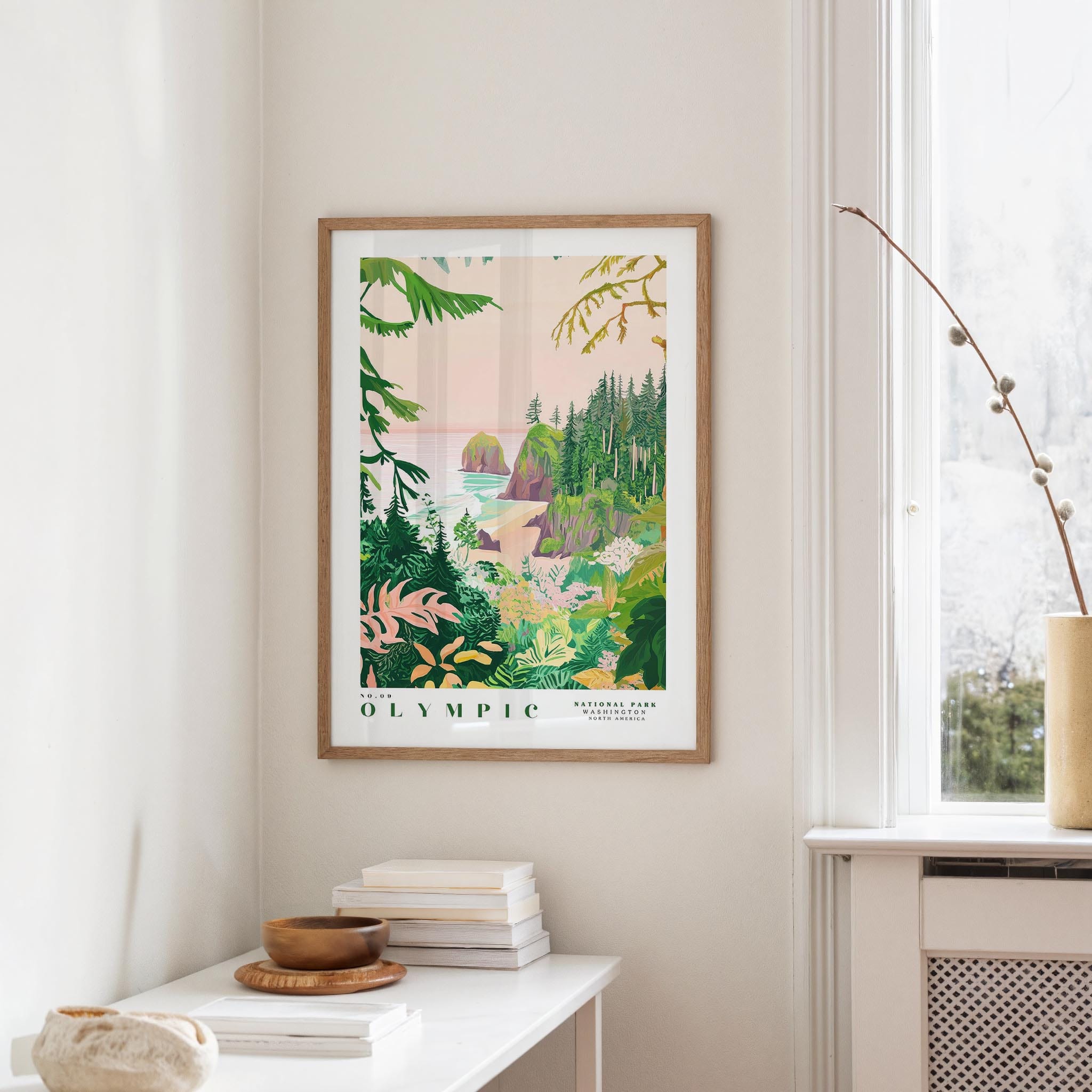 a framed poster of a tropical landscape hanging on a wall, with a white table and a plant in the foreground.