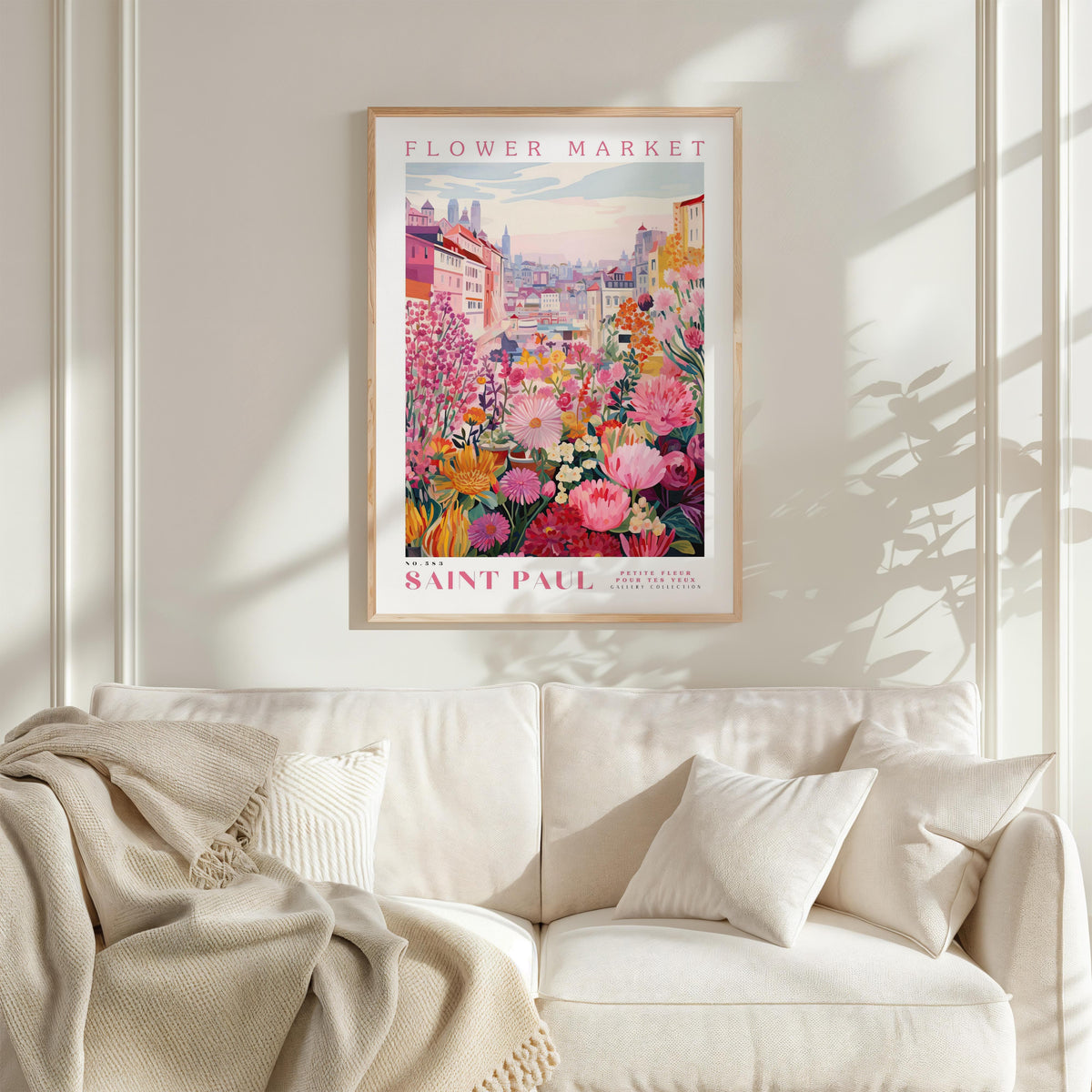 a poster of a flower market in Saint Paul, with a colorful and vibrant illustration of flowers and buildings. The poster is hung on a wall above a white couch, creating a cozy and inviting atmosphere in the room.