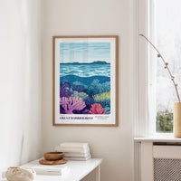 a framed poster of a vibrant underwater scene, depicting a coral reef with various marine life, hanging on a wall in a room with a white table and a window.