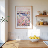 a kitchen scene with a framed poster of a flower market in Perth, a wooden counter with a bowl of lemons, and shelves displaying various jars and containers.