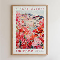 The image is a framed poster depicting a vibrant and colorful scene of a flower market in a town, with buildings, flowers, and a river in the background.