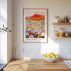 a framed poster of a desert landscape with cacti and flowers, hanging on a wall above a wooden countertop with a bowl of lemons.