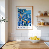 a framed poster of a coastal landscape with a lighthouse, hanging on a wall above a wooden countertop with a bowl of lemons.