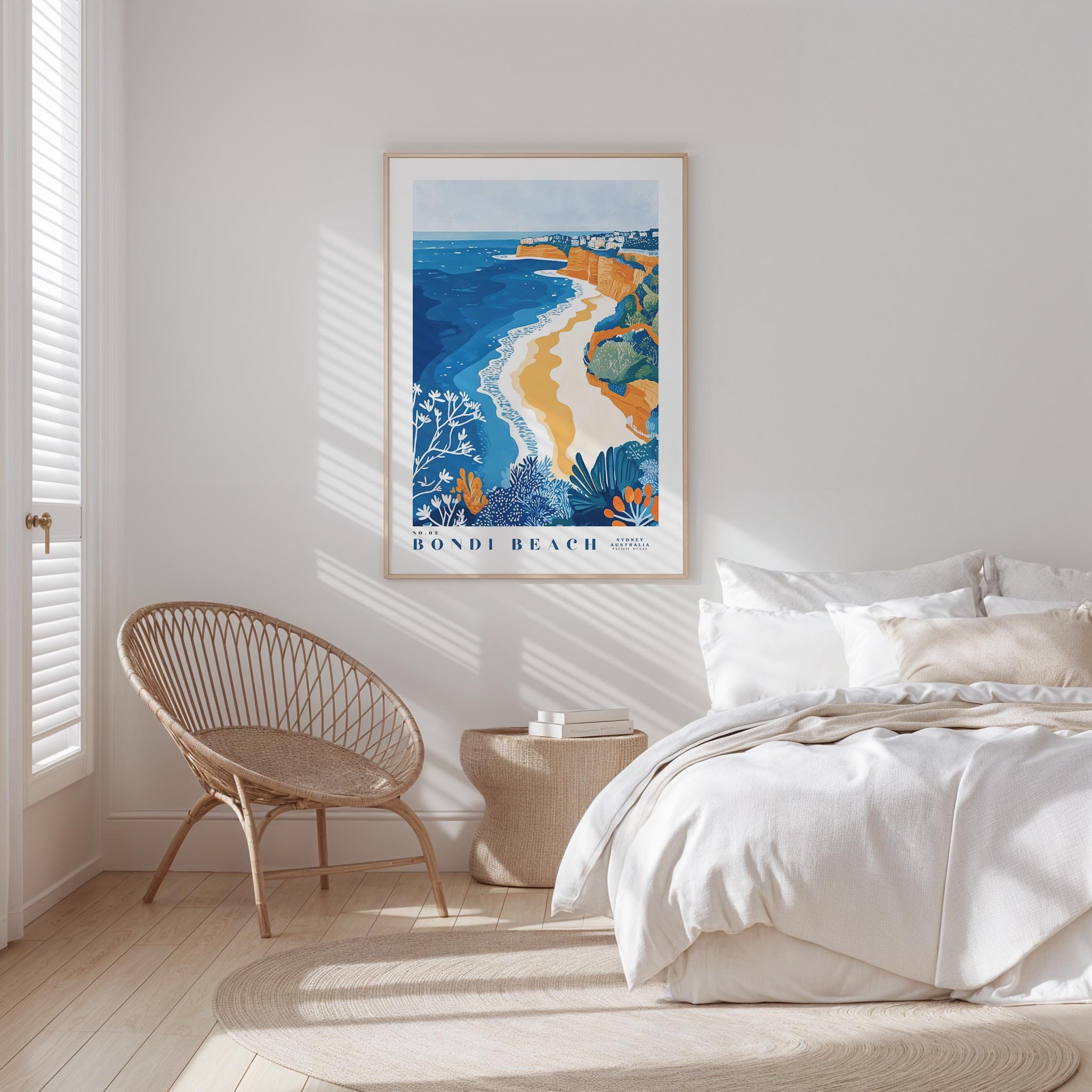 a serene bedroom scene with a large framed poster of Bondi Beach hanging on the wall, a wicker chair, and a neatly made bed with white bedding.