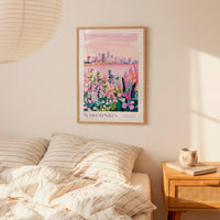 a bedroom scene with a framed poster of a cityscape of Wisconsin hanging on the wall above a bed with striped pillows.