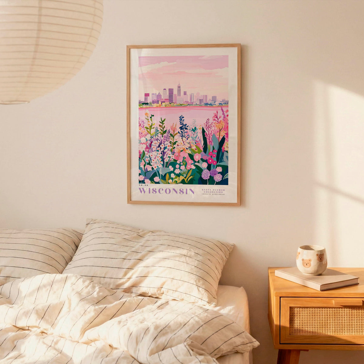 a bedroom scene with a framed poster of a cityscape of Wisconsin hanging on the wall above a bed with striped pillows.