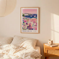 a bedroom setting with a framed poster of a colorful coastal scene hanging on the wall above a bed with striped pillows.