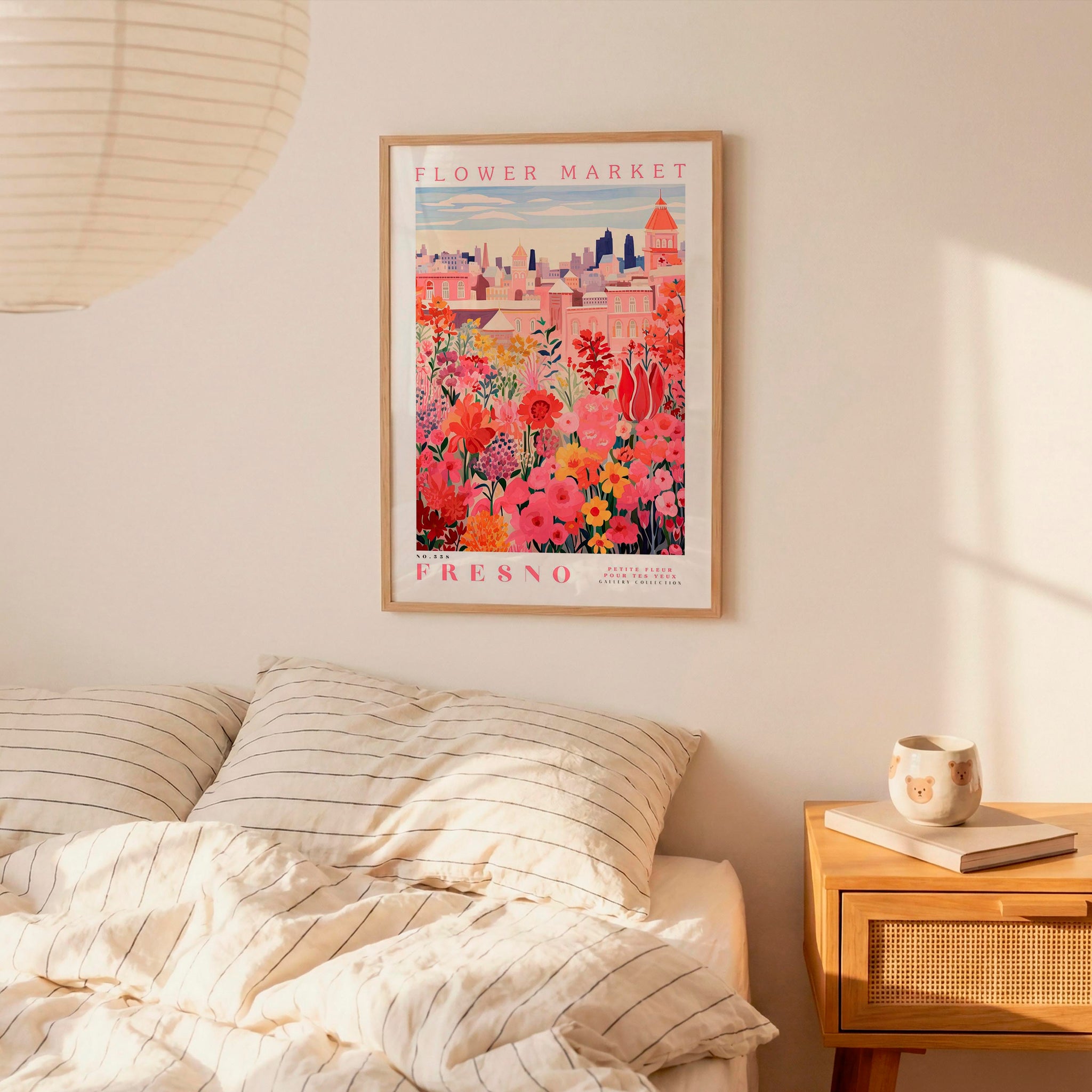 a framed poster of a colorful floral scene hanging on a wall above a bed with striped pillows.