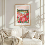 a framed poster of a vibrant floral landscape hanging on a wall above a white couch with a blanket draped over it.