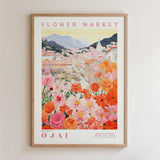 The image is a framed poster depicting a vibrant and colorful flower market in Ojai, with a variety of flowers and buildings in the background.